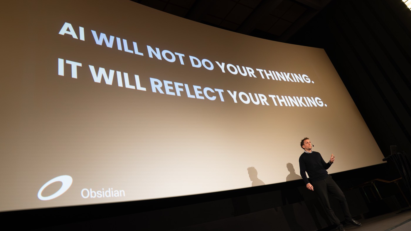 Nicklas Lindby holder AI-foredrag på Marketing Morning 2026 i Helsinki foran et stort lærred med teksten "AI will not do your thinking. It will reflect your thinking"